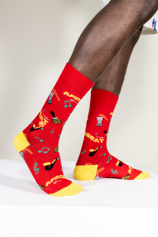 Red socks. Afrobeat socks is a celebration of Afrobeat. The West African music genre was pioneered in the 1960s by Nigerian artist, Fela Kuti. It is a mixture of traditional Yoruba music such as fuji and other contemporary sounds of the time, like jazz and soul.
Instruments on socks: shekere, djembe drum, talking drum, saxophone