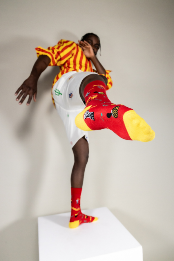 Red socks. Afrobeat socks is a celebration of Afrobeat. The West African music genre was pioneered in the 1960s by Nigerian artist, Fela Kuti. It is a mixture of traditional Yoruba music such as fuji and other contemporary sounds of the time, like jazz and soul.
Instruments on socks: shekere, djembe drum, talking drum, saxophone