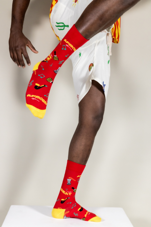 Red socks. Afrobeat socks is a celebration of Afrobeat. The West African music genre was pioneered in the 1960s by Nigerian artist, Fela Kuti. It is a mixture of traditional Yoruba music such as fuji and other contemporary sounds of the time, like jazz and soul.
Instruments on socks: shekere, djembe drum, talking drum, saxophone