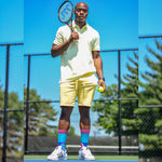Black man holding a tennis racket and wearing a yellow outfit, with blue sock